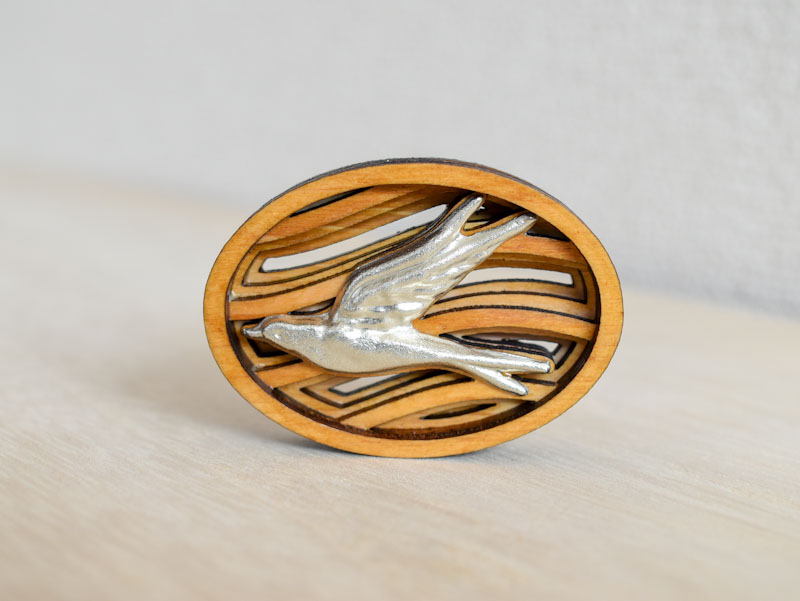 空を飛ぶツバメをモチーフとしたブローチの正面からの画像。